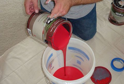 pouring a gallon of red paint into a five gallon bucket