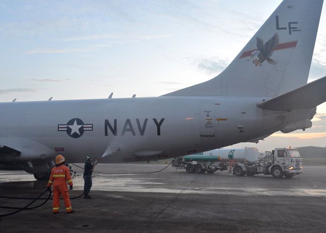 U.S. Navy Aviation Structural Mechanic 2nd Class Matthew Walton sprays down a P-8A Poseidon with before its flight to assist in search and rescue operations for MH370.