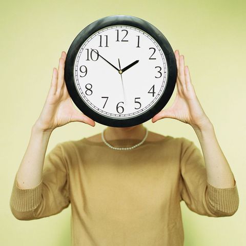 Woman with clock in front of face