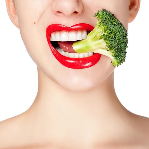 Woman biting broccoli