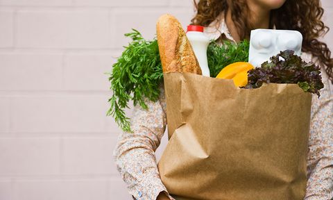 woman carrying brown bag full of vegetables