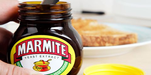 A man getting Marmite out of the jar with a knife