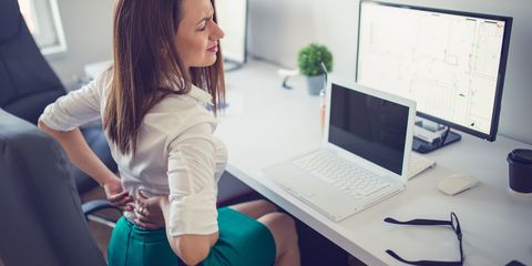Woman sat at desk in office with lower back pain