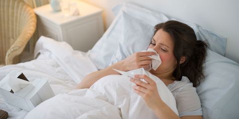 Woman in bed feeling ill with flu and temperature
