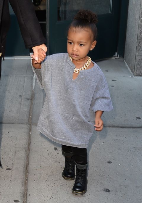 <p>She channels her dad Yeezy wearing an oversized grey sweatshirt poncho, black leather leggings, motorcycle boots, and a thick gold chain necklace</p>