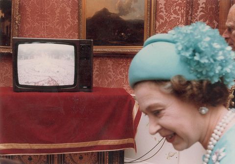 <p>Queen Elizabeth smiles as she watches the TV.</p>