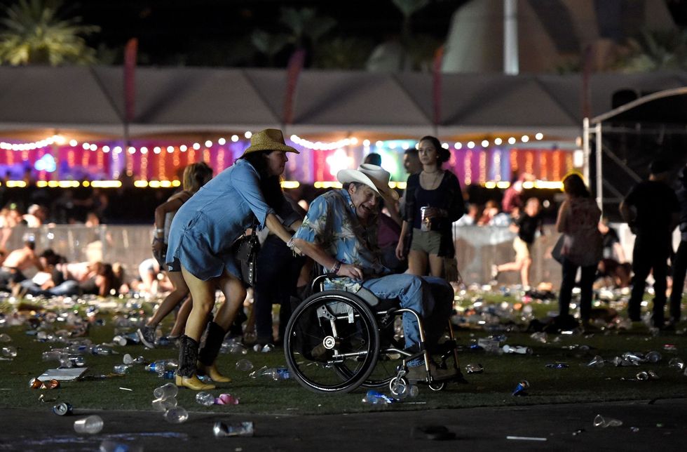 <p>A woman pushes a man in a wheelchair as concertgoers seek cover. </p>