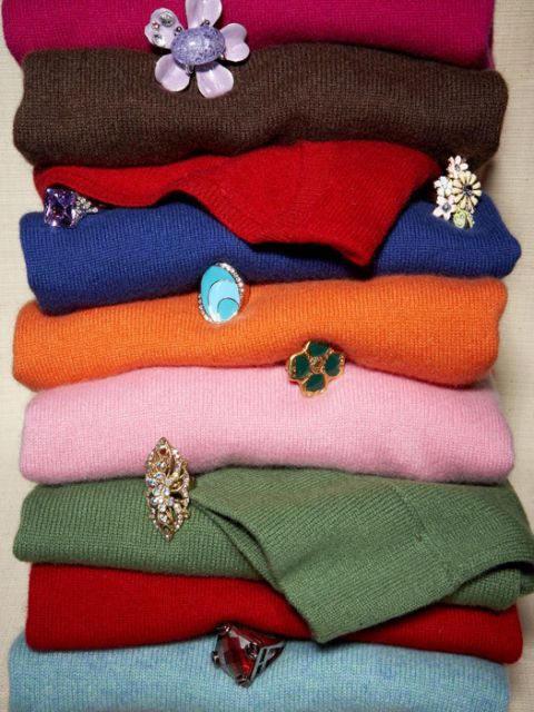 colorful cashmere sweaters folded in pile with cocktail rings