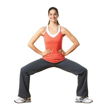 woman on white background doing ballet squat in exercise clothes