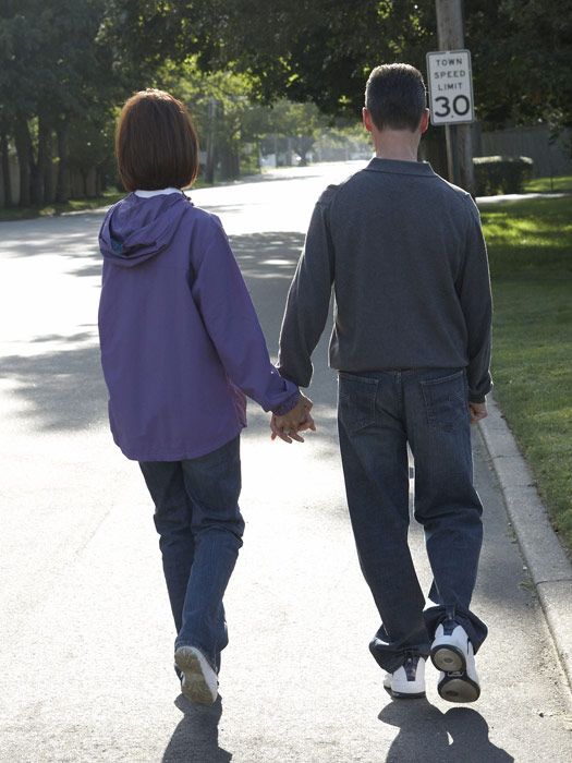 couple holding hands walking down street