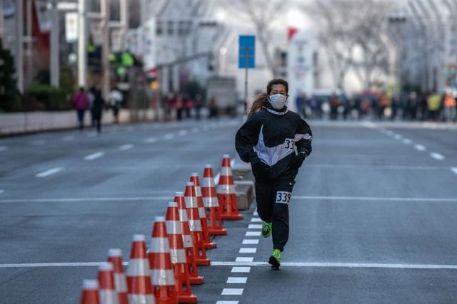 Una top runner effettua il riscaldamento con la mascherina alla Tokyo Marathon chiusa agli amatori per l'emergenza Coronavirus ( )