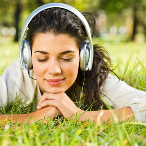 girl laying in the grass with head phones on looking calm