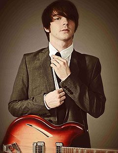drake bell in a suit holding a guitar