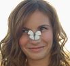 brown haired girl in sunshine with white butterfly on nose