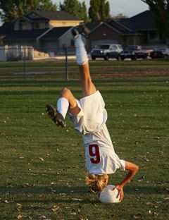 soccer player upside down about to fall on her head