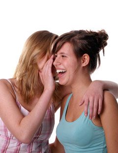 girl whispering in another girls ear