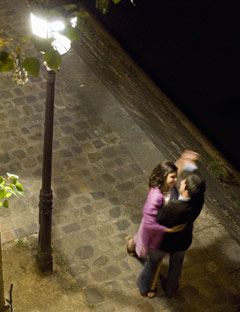 a couple dancing on a city sidewalk at night