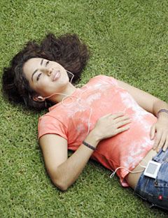 girl lying on grass listening to music