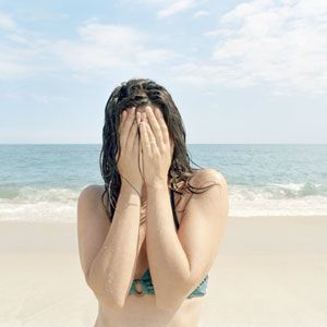 girl covering her face at the beach