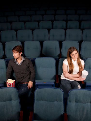 An angry couple sitting in a movie theater.