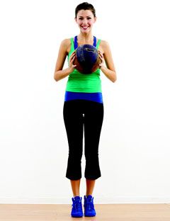 girl standing and holding exercise ball in front of her chest