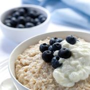 oatmeal with cream and blueberries on top in a bowl
