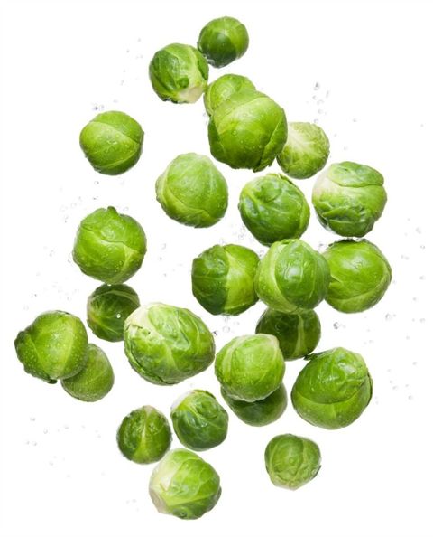 Healthy eating clean organic fresh vegetable brussel sprouts flying and bouncing up into the air in studio on a white background for wellness