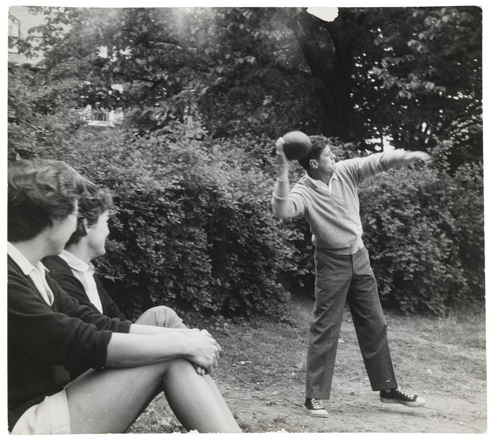 JFK in sneakers throwing a football as his sister-in-law Ethel and Jackie Kennedy spectate.