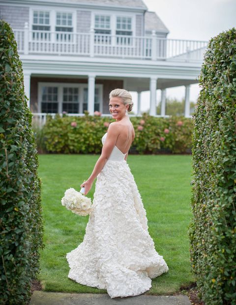 The beautiful bride amongst the hedges in her yard.