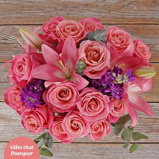 Bouquet of pink roses next to a gift with a happy birthday card
