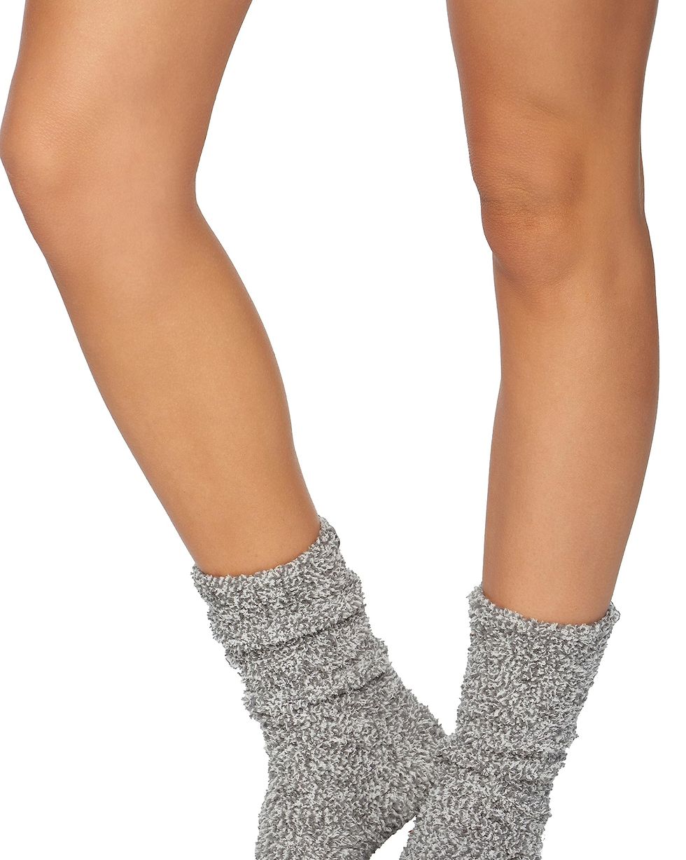Cropped view of woman putting her feet in warm comfy socks on