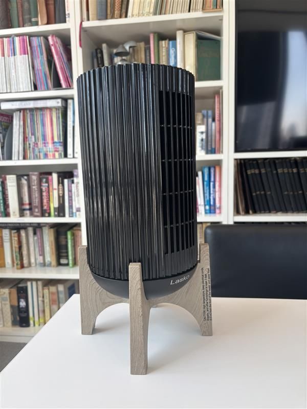Vertical black electric heater on a light wooden stand