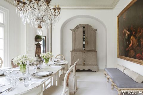 <p>The dining room floors were painted a custom high-gloss color to give the antiques a fresh look. Gustavian buffet à deux corps, 18th-century Swedish bench, and 19th-Century Italian chandelier, Tara Shaw Antiques; table, Tara Shaw Maison; walls in a custom Fine Paints of Europe color.</p>