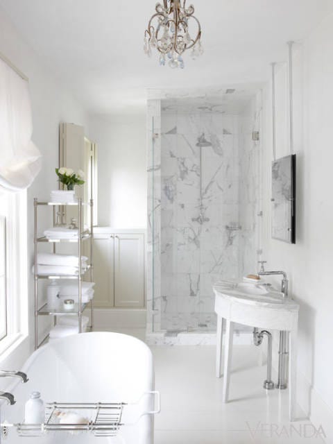 Luxurious white bathroom with marble shower, Gustavian antique console table vanity, mirror hung from ceiling, and freestanding tub. #whitebathroom #bathroomdecor #luxurious #pamelapierce #Gustavian