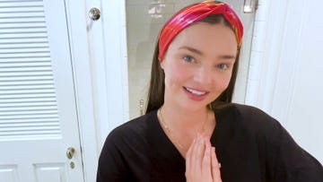 miranda kerr stands in her bathroom she is wearing a black shirt and a red bandana