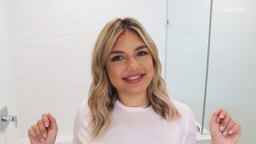 giannina gibelli sits in her white tiles bathroom she is wearing a whit teeshirt and smiling into the camera