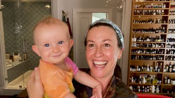 alanis morissette holders her smiling baby as she stands in her bathroom