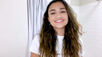 madison bailey smiles into the camera she is standing in her all white bathroom wearing a white teeshirt