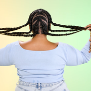 woman shows off crisscross braids in front of a yellow to green gradient background