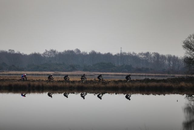 zes mountainbikers langs het water met weerspiegeling tijdens drenthe 200