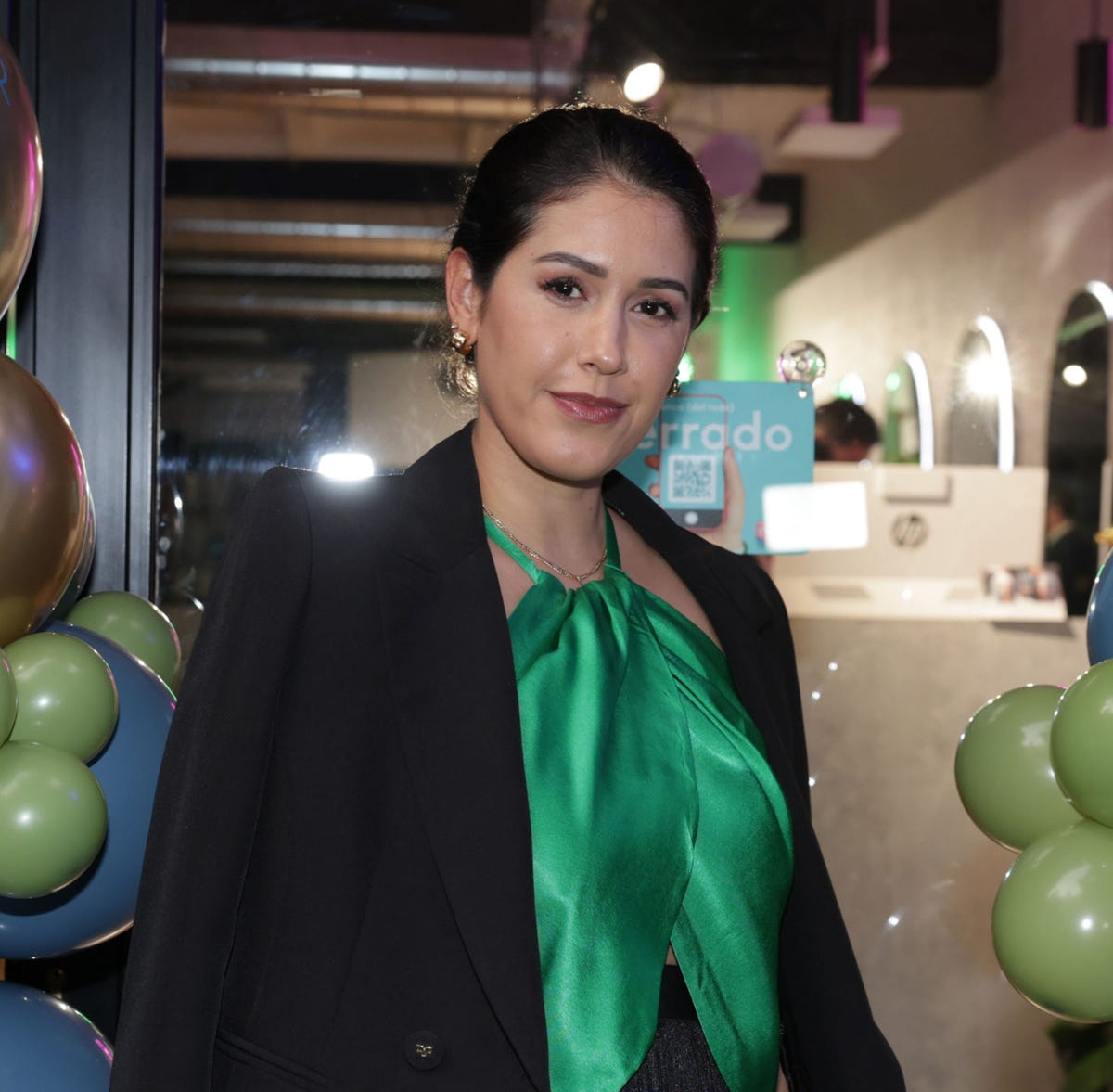 la empresaria con top verde y americana negra