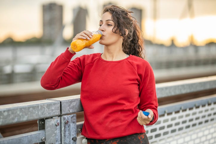 young woman holding glass of apple juice and fresh apple