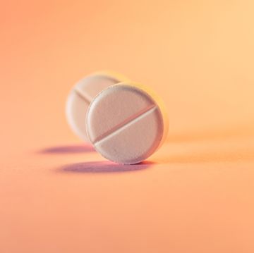 two pills in an orangepink background medical theme