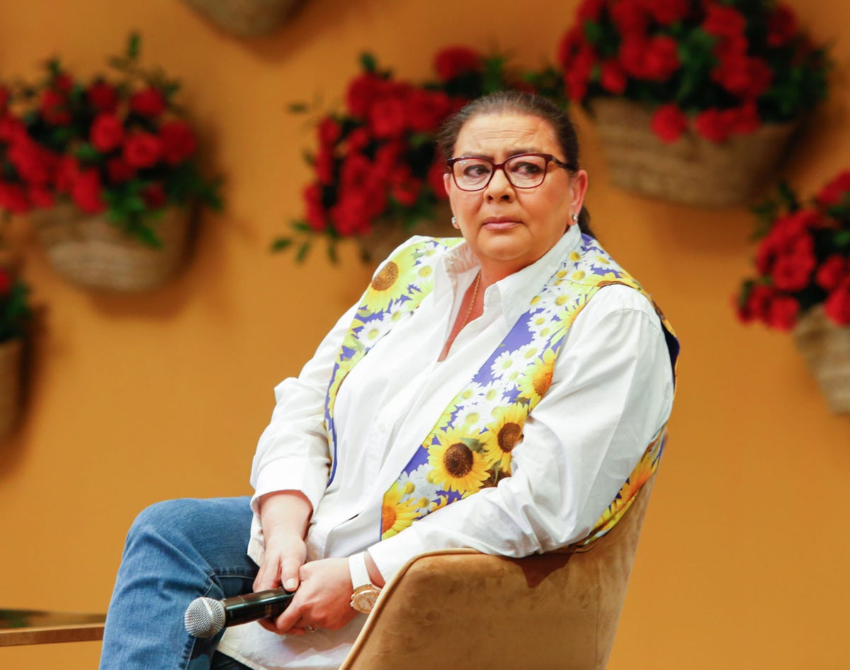 la cantante triste con camisa blanca y chaleco de margaritas y girasoles