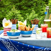 july 4th food picnic table with bowls of dips chips and pretzels and pitcher of lemonade