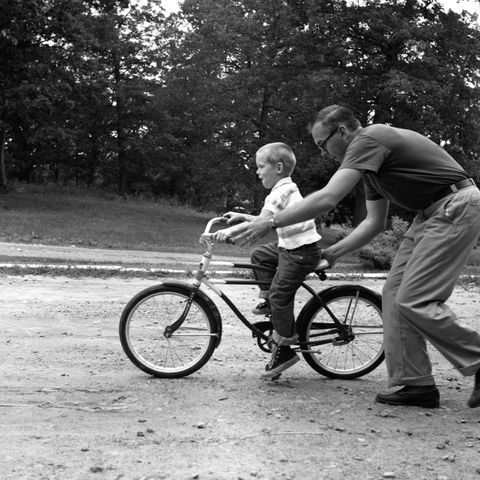 father son riding bicycle no helmet
