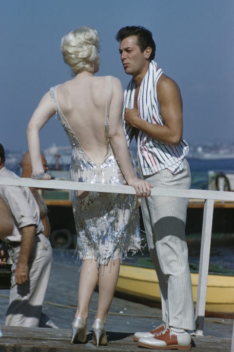 image American actors Marilyn Monroe (1926-1962) and Tony Curtis (1925-2010) pictured together on location near San Diego, California during production of the film 'Some Like It Hot' in 1958. Marilyn Monroe and Tony Curtis play the characters of Sugar Kane Kowalczyk and Joe/Josephine in the film. (Photo by Rolls Press/Popperfoto/Getty Images)