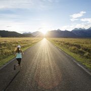 health and fitness quotes woman running down an empty road with grass on both sides and mountains in the distance