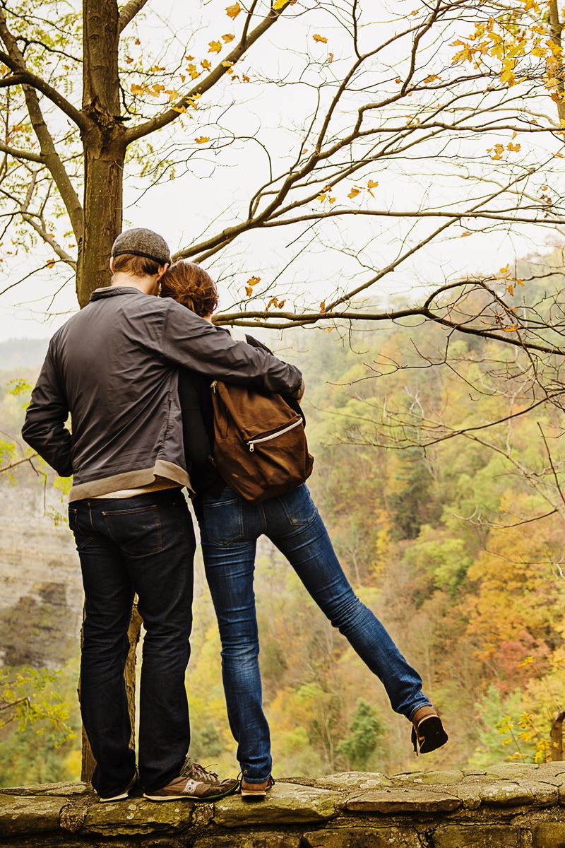 fall date ideas backside of hugging couples as they look out at the view of fall foliage at the top of a mountain