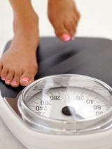 High: Being 20 Pounds Overweight woman stepping on scale